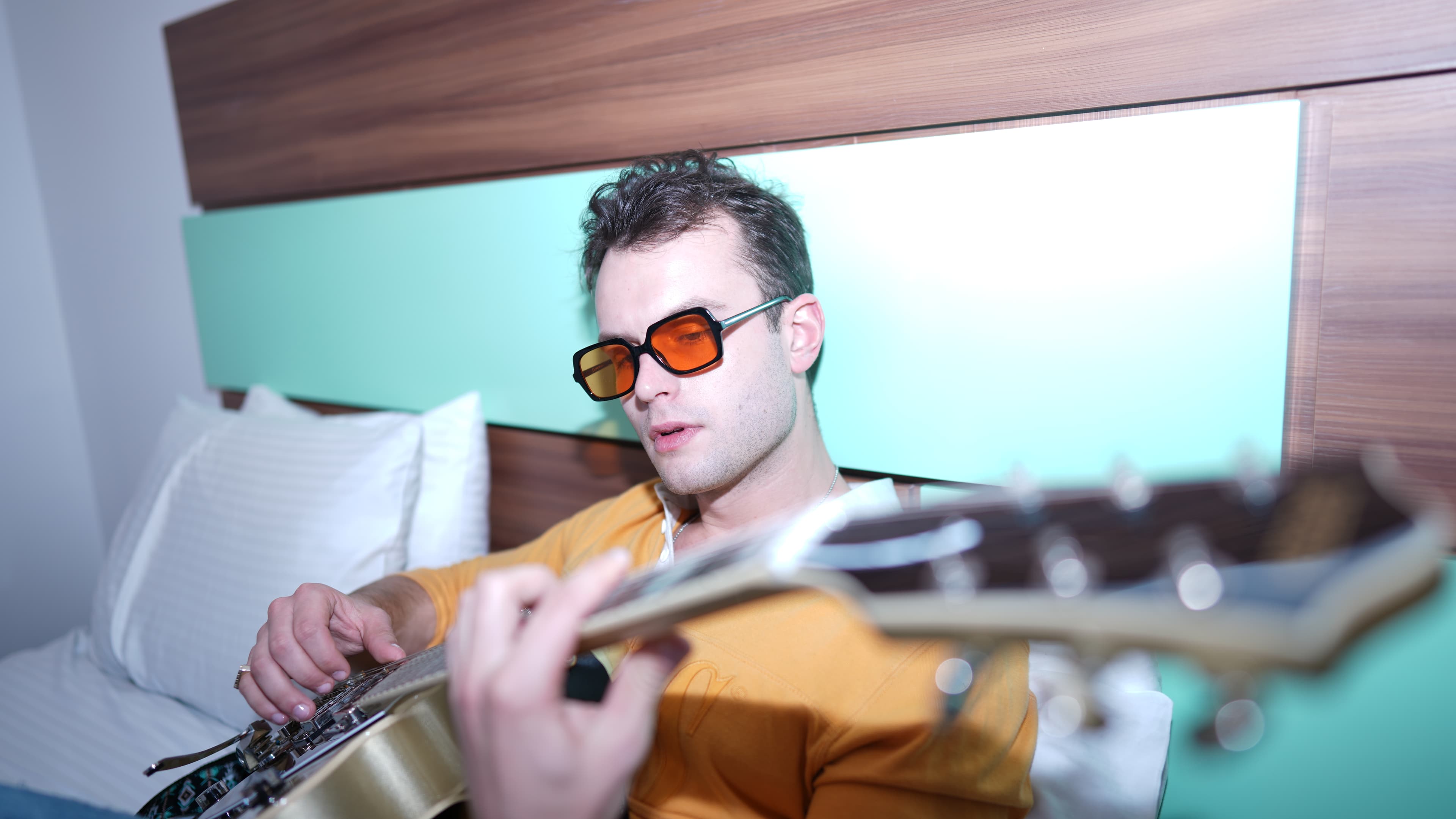 GRAUX playing guitar on a hotel bed  ·  the kind of session where a $99 guitar and an iPhone became a Ricky Martin placement